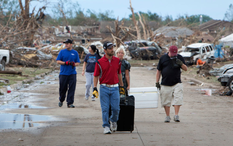 Residents remove their belongings from a residential area in Moore, Oklahoma May 21, 2013 after a massive tornado struck the area May 20. Emergency workers pulled more than 100 survivors from the rubble of homes, schools and a hospital in an Oklahoma town hit by a powerful tornado May 20, and officials lowered the death toll from the storm to 24, including nine children.