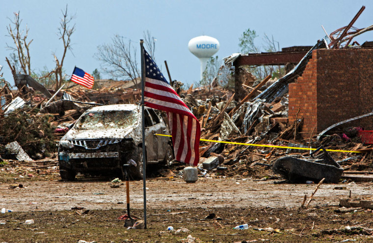 American flags wave over the remains of Plaza Towers Elementary school in Moore, Oklahoma May 21, 2013 after it was destroyed by a massive tornado May 20. Emergency workers pulled more than 100 survivors from the rubble of homes, schools and a hospital in an Oklahoma town hit by a powerful tornado, and officials lowered the death toll from the storm to 24, including nine children.