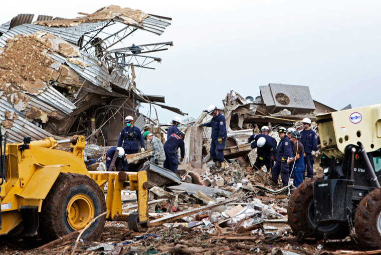 Rescue workers look through the rubble at Plaza Towers Elementary school in Moore, Oklahoma May 21, 2013 after a devastating tornado ripped through the town May 20. Officials report that he 2-mile (3-km) wide tornado has killed at least 24 people and injured more than 200 others.