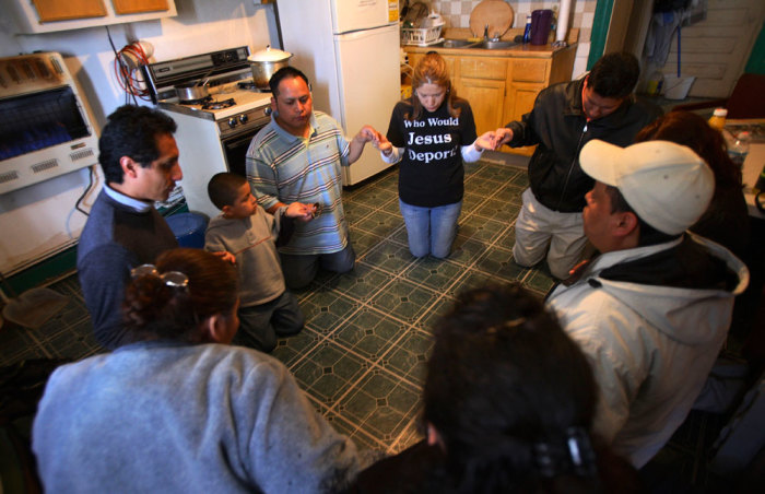 Elvira Arellano (C) prays with other illegal immigrants in the kitchen of her apartment in the Adalberto United Methodist Church in Chicago April 15, 2007. April 15th marked the 8th month that Mexican-born Arellano, 32, has been fighting a deportation order from inside the Chicago church where she has imprisoned herself, invoking the ancient medieval protection of sanctuary.