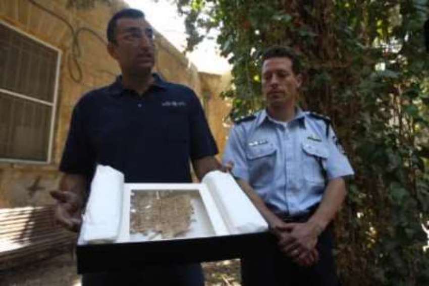 Israeli police spokesperson Micky Rosenfeld (R) and Amir Ganor, director of the unit for the prevention of antiquities robbery in the Israeli Antiquities Authority, show a document, thought to be an ancient text written on papyrus, at Jerusalem Magistrates Court May 6, 2009.