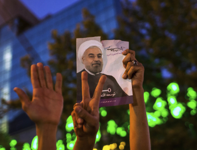Supporters of moderate cleric Hassan Rohani hold a picture of him as they celebrate his victory in Iran's presidential election on a pedestrian bridge in Tehran June 15, 2013. Rohani won Iran's presidential election, scoring a surprising landslide victory over conservative hardliners without the need for a second round run-off.