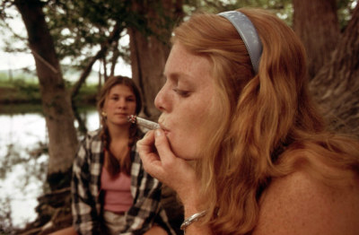 A young woman smokes a marijuana cigarette while her friend watches in this photo taken by St. Gil, Marc, and made available by the U.S. National Archives.