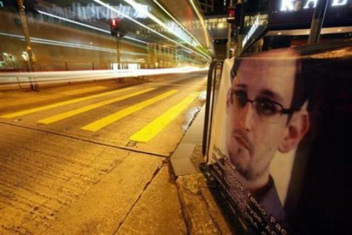 A bus passes by a poster of Edward Snowden, a former contractor at the National Security Agency (NSA), displayed by his supporters at Hong Kong's financial central district during the midnight hours, while Snowden is engaged in a live chat online believed to be in Hong Kong, on June 18, 2013.