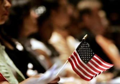 A woman holds an American flag during naturalization ceremonies for new citizens aboard the Intrepid in New York