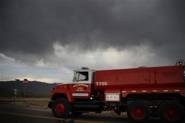 A vehicle travels near monsoon storm cells passing over Yarnell area with rain that helped firefighters in Congress, Arizona July 1, 2013, a day after an elite squad of 19 Arizona firefighters were killed in the worst U.S. wildland fire tragedy in 80 years.