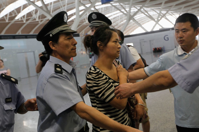 The mother (C) of Wang Linjia, one of the two girls killed during the Asiana Airlines plane crash on Saturday, leaves for San Francisco from Shanghai Pudong airport, July 8, 2013. An emergency vehicle rushing to the scene of the Asiana Airlines crash at San Francisco's international airport may have run over one of the two teenage Chinese girls killed in the incident, the local fire department said on Sunday.