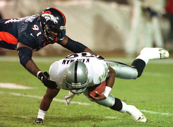 Denver Broncos defensive end Alfred Williams (L) tackles Oakland Raiders Napoleon Kaufman for a six-yard loss during the first quarter of their NFL game in Denver on November 24, 1997. Kaufman ran for over two hundred yards against the Broncos in their first match-up of the season in Oakland.