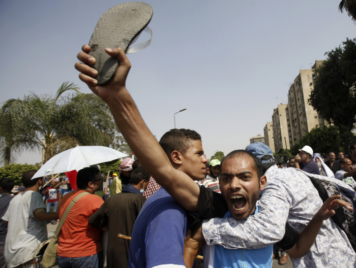 A member of the Muslim Brotherhood and supporters of deposed Egyptian President Mohamed Mursi shout slogans in front of army soldiers at Republican Guard headquarters in Nasr City, a suburb of Cairo July 8, 2013.