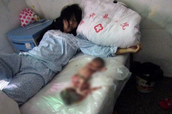 A Chinese woman lies beside her poisoned and deceased newborn, a procedure ordered by the Chinese government.