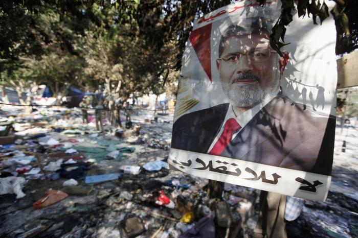 A poster of deposed president Mohamed Mursi which reads, 'No to the coup', is near debris of a protest camp outside the burnt Rabaa Adawiya mosque, in Cairo, August 15, 2013. Egypt's Muslim Brotherhood called on followers to march in protest in Cairo on Thursday, after at least 525 people were killed in a security crackdown on the Islamist movement that has left the most populous Arab nation polarized and in turmoil.