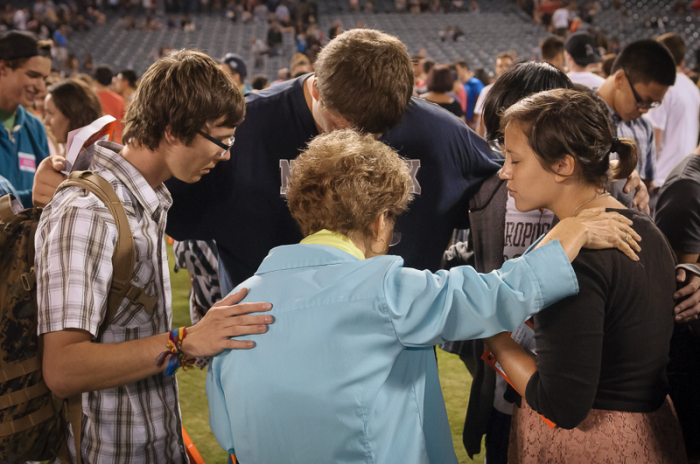 Group on the field at Angel Stadium during 'altar call' at SoCal Harvest 2013 pray together after evangelist Greg Laurie's invitation to accept Jesus Christ, Aug. 25, 2013.