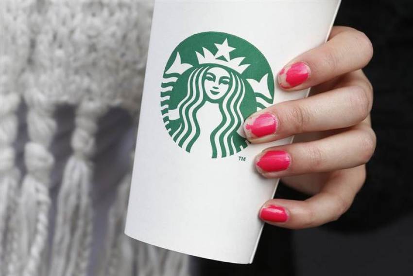 A woman holds a Starbucks takeaway cup in this October 24, 2012 file photo. Starbucks has asked workers in its Washington-area shops to write "come together" on customers cups as a message to lawmakers to agree to a budget deal.