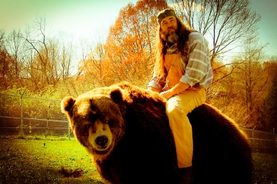 'Bear Man' Jeff Watson sits atop one of his 'pets,' whom he leads around in shows and in truffle hunts to raise money for their feed.
