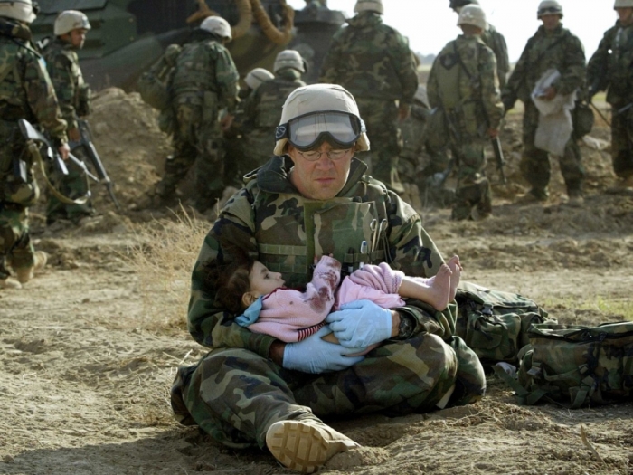 U.S. Navy Hospital Corpsman HM1 Richard Barnett, assigned to the 1st Marine Division, holds an Iraqi child in central Iraq on March 29, 2003.