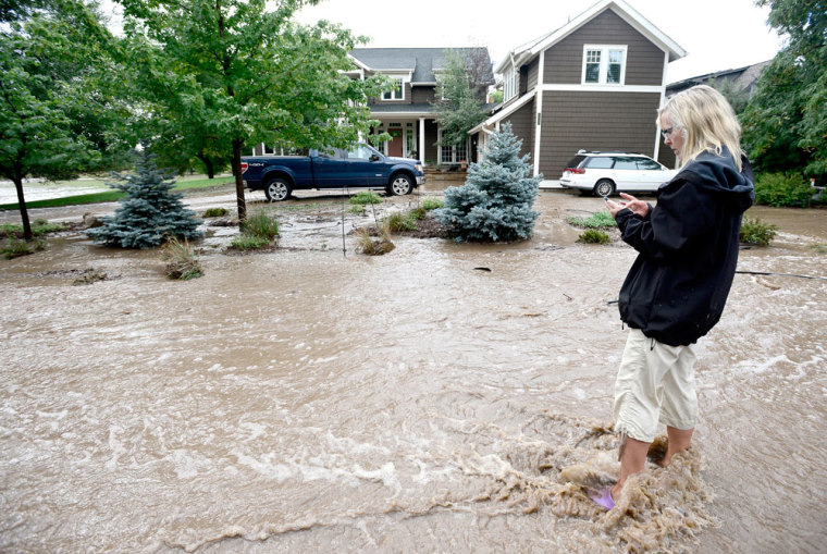Carolyn Hornung stands in running water in front of her house calling friends to let them know she is alright after heavy rains caused flooding in Boulder, Colorado September 13, 2013. The National Guard on Friday evacuated a Colorado town cut off by raging floodwaters, while forecasters called for some let-up in record rains that have killed three people, washed out dams and swamped roads across the state.