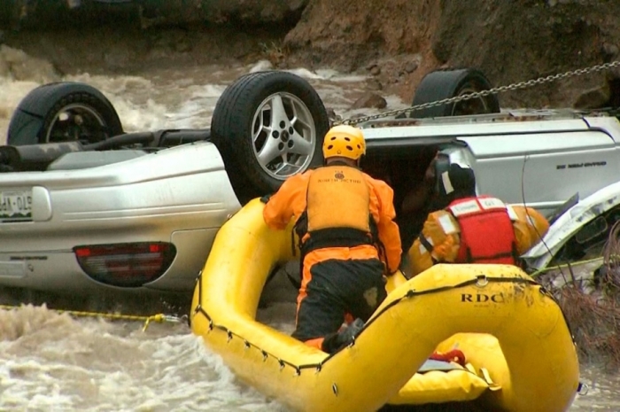 Emergency personnel work to rescue a man trapped in his vehicle during flooding of Rock Creek in Lafayette, Colo.