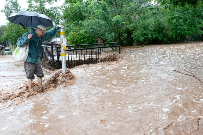 Matthew Messner looks for a way to cross where water from heavy rains in Boulder overflowed the sidewalk.