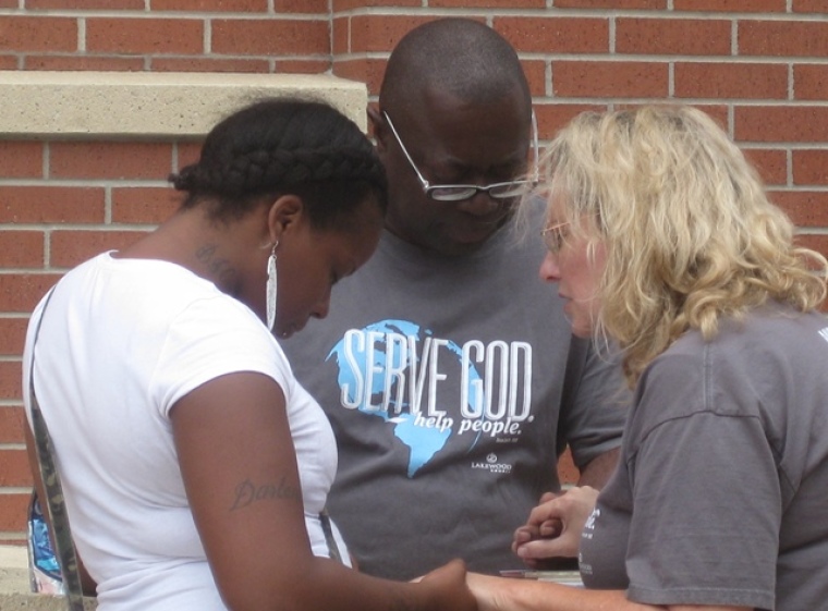 Lakewood Church street evangelism volunteers pray with a woman outside a Harris County jail in Houston, Texas, on Sept. 21, 2013.