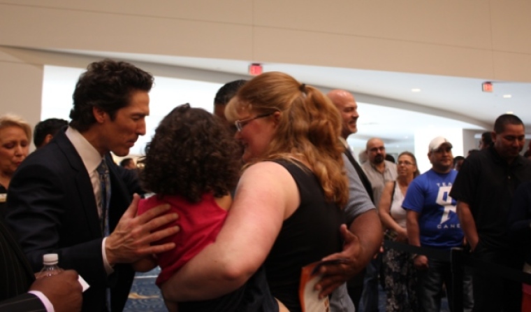 Pastor Joel Osteen prays with a young family who visited Lakewood Church to attend a Sunday morning worship service in Houston, Texas, Sept. 22, 2013.