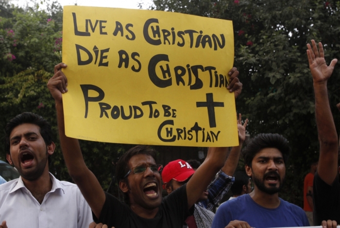 A member of the Pakistani Christian community holds a placard as he shouts slogans during a protest rally to condemn Sunday's suicide attack in Peshawar on a church, with others in Lahore, Pakistan, September 23, 2014.