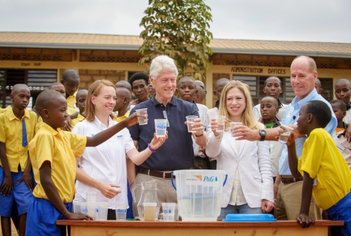 President Bill Clinton and Chelsea Clinton join World Vision's Dr. Greg Allgood and Procter & Gamble's Allison Tummon Kamphuis in bringing clean water to Rwandan children through the aid of P&G water purification packets.