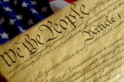 The United States Constitution with flag background.