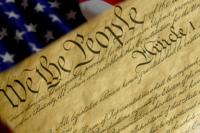 The United States Constitution with flag background.