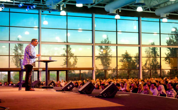 Pastor Rick Warren stands on stage at Saddleback Church in Lake Forest, Calif. The megachurch this month is launching three international campuses, one in Hong Kong, Buenos Aires, and Berlin.