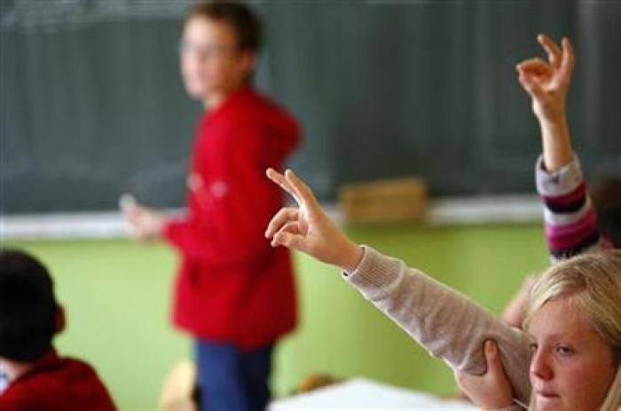 Students raise their hands to answer a question during their class in a Catholic school in Sarajevo, Bosnia, October 16, 2009.