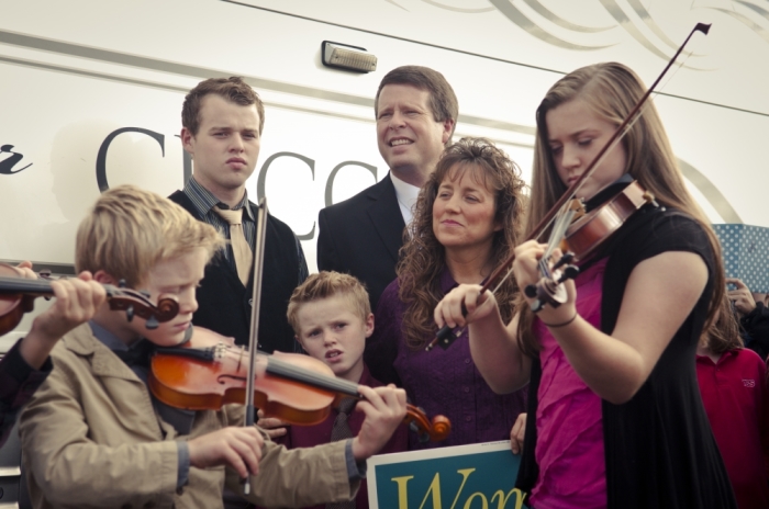 Jim Bob Duggar, former state senator and father of 19 children, stands with his wife Michelle as their children play their violins.