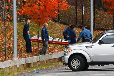 Investigators, including representatives from the state's Medical Examiner's office, pull the body of Colleen Ritzer, 24, from the woods behind Danvers High School on Wednesday.