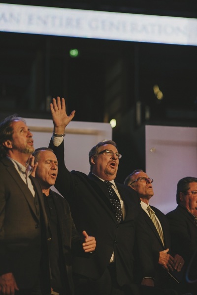 Pastor Rick Warren (center) along with other pastors, including Bob Coy (far left) and Raul Reies (2nd from left), stand during worship music portion of tribute to Pastor Chuck Smith in Anheim, Calif., Oct. 28, 2013.