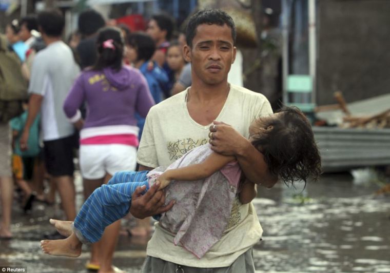 A father carries the body of his daughter to the morgue after super typhoon Haiyan hit Tacloban City in Leyte province