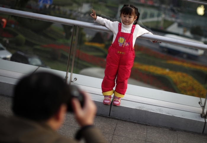 A girl poses for a photograph at a commercial area of downtown Shanghai in this 2012 file photo. China has eased its one-child policy, and ended its controversial Labor Camp program.