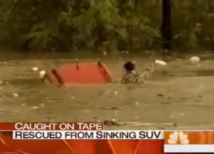 Woman is rescued from sinking SUV engulfed in flood waters.