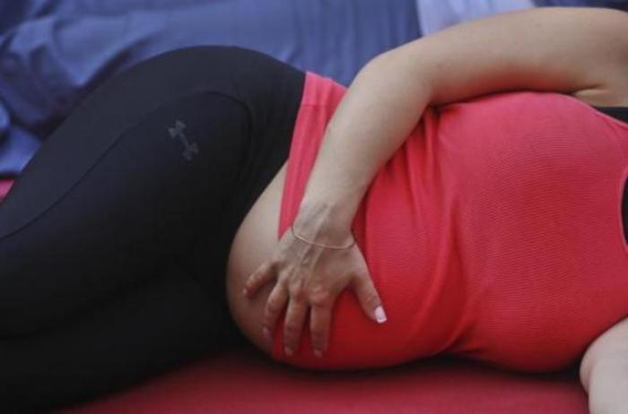 A pregnant woman touches her stomach as people practice yoga on the morning of the summer solstice in New York's Times Square June 20, 2012.