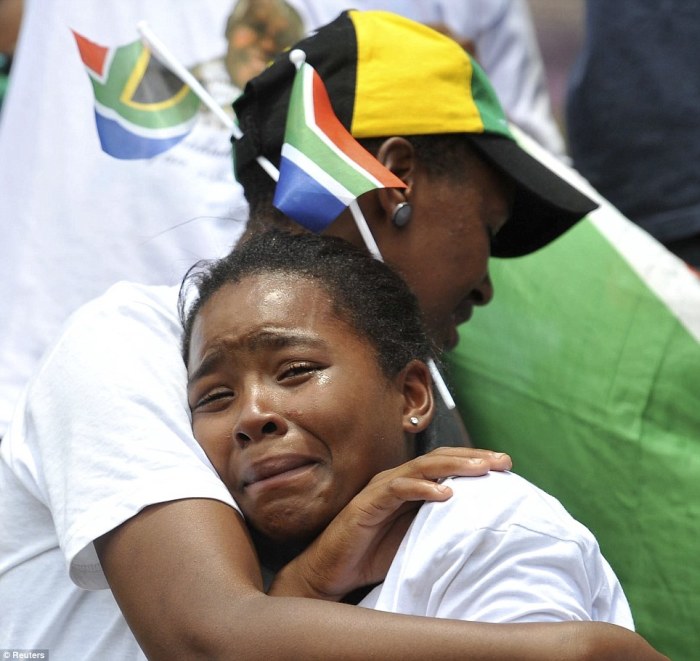 Mourners console each other as they watch a broadcast of the state funeral of former South African President Nelson Mandela, at Orlando Stadium in Johannesburg.