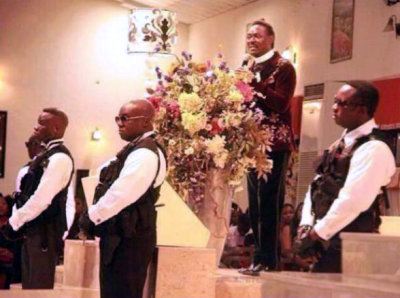 Nigerian Pastor Chris Okotie preaches from the pulpit flanked by armed guards during a service at his Household of God Church in Lagos, Nigeria, on Sunday, Dec. 8, 2013.