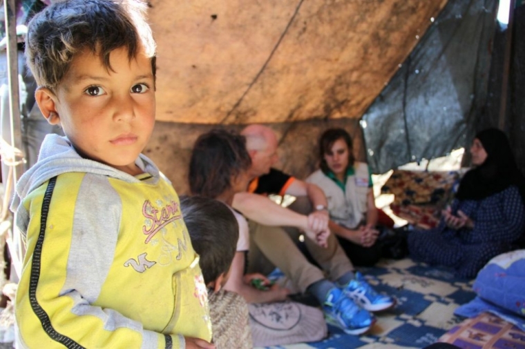 A Syrian refugee peers out from a tent in one of the makeshift settlements in Lebanon