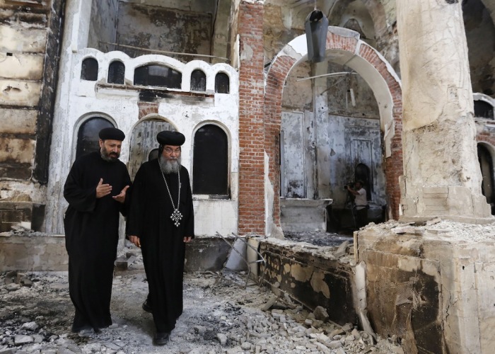 Bishop-General Macarius (R), a Coptic Orthodox leader, walks around the burnt Evangelical Church in Minya governorate, south of Cairo, August 26, 2013.