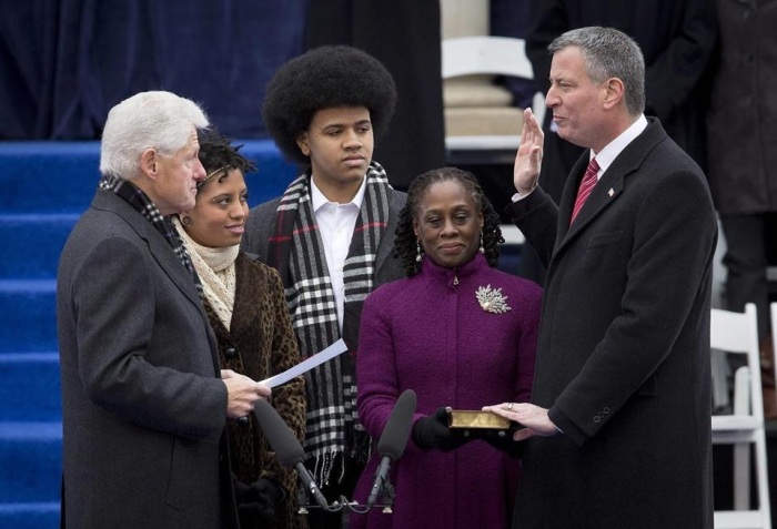 New York City Mayor Bill de Blasio (R) raises his right hand as former U.S. President Bill Clinton administers the oath of office during De Blasio's formal inauguration ceremony on the steps of City Hall in New York Jan. 1, 2014.
