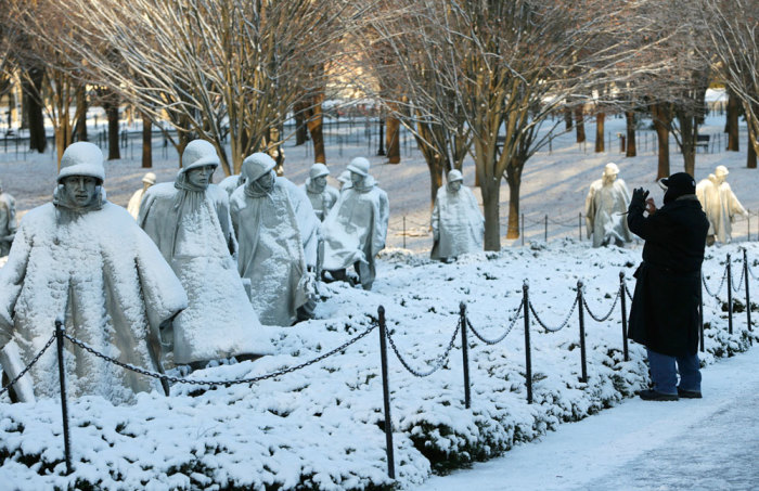 A man photographs the Korean War Veterans Memorial after a heavy snow storm in Washington January 3, 2014. A heavy snowstorm and dangerously cold conditions gripped the northeastern United States on Friday, delaying flights, paralyzing road travel and closing schools and government offices across the region.