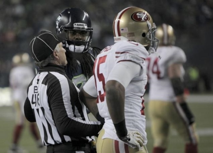 NFL official steps in as Richard Sherman appears to mock Michael Crabtree after tipping away pass intended for the receiver in the end zone, preserving a playoff victory for the Seattle Seahawks over the San Francisco 49ers, Jan. 19, 2014.