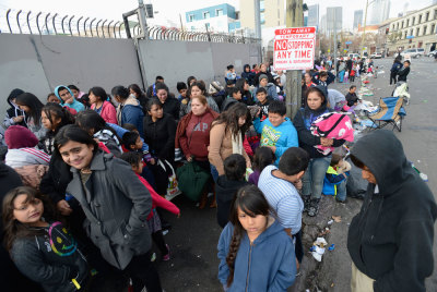 Children and families wait in line, as holiday gifts and toys are distributed to underprivileged children at the Fred Jordan Mission in Los Angeles December 21, 2013.