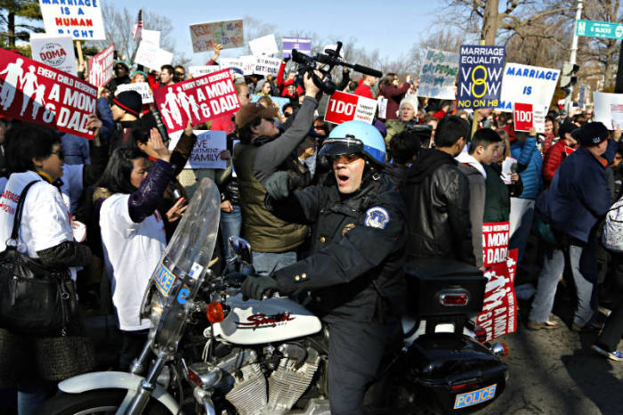 A policeman pushes traditional marriage supporters from the street in front of the U.S. Supreme Court in Washington, March 26, 2013.