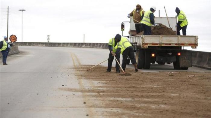 Workers with the city of Mobile shovel dirt on a bridge as cold weather descends on Mobile, Alabama January 28, 2014.