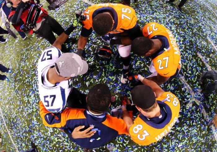 Seattle Seahawks linebacker Mike Morgan (# 57) prays with members of the Denver Broncos after his team handed them a devastating 43-8 loss in the NFL's Super Bowl 2014 on Sunday.