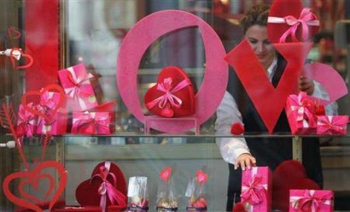 A vendor adjusts decorative red hearts and praline boxes behind the window of a Belgian chocolate shop ahead of Valentine's Day in Brussels, Belgium, Feb. 13, 2007.