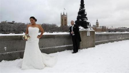 A newly married couple pose for a photograph in the snow opposite the Houses of Parliament, in central London, in this Dec. 18, 2010 file photo.